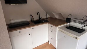 Et lille tekøkken med vask, komfur og mikroovn.