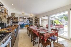 Cucina spaziosa con zona pranzo, ampie finestre e parete in pietra.