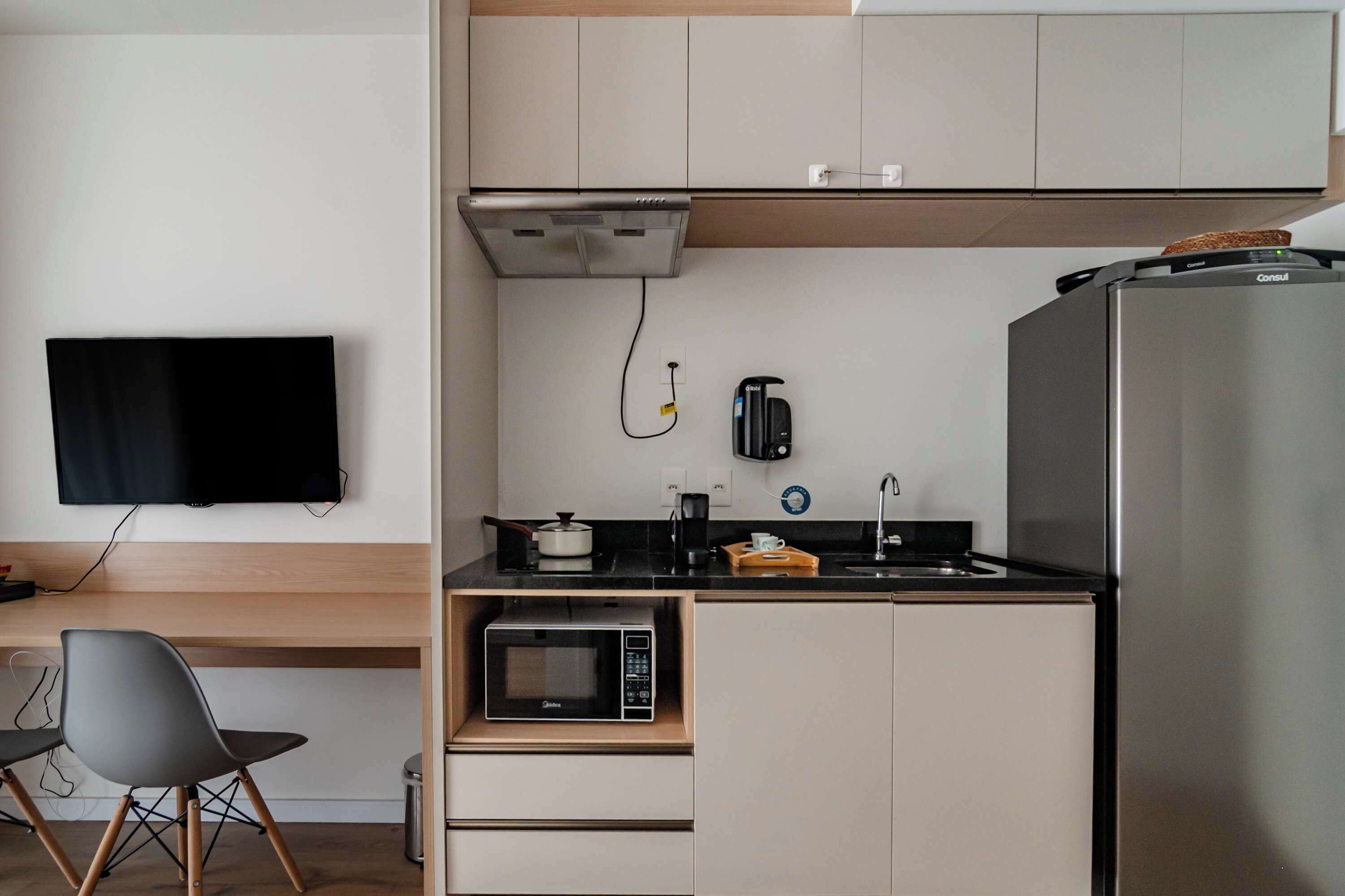 A compact kitchen with a microwave, coffee maker, and refrigerator.