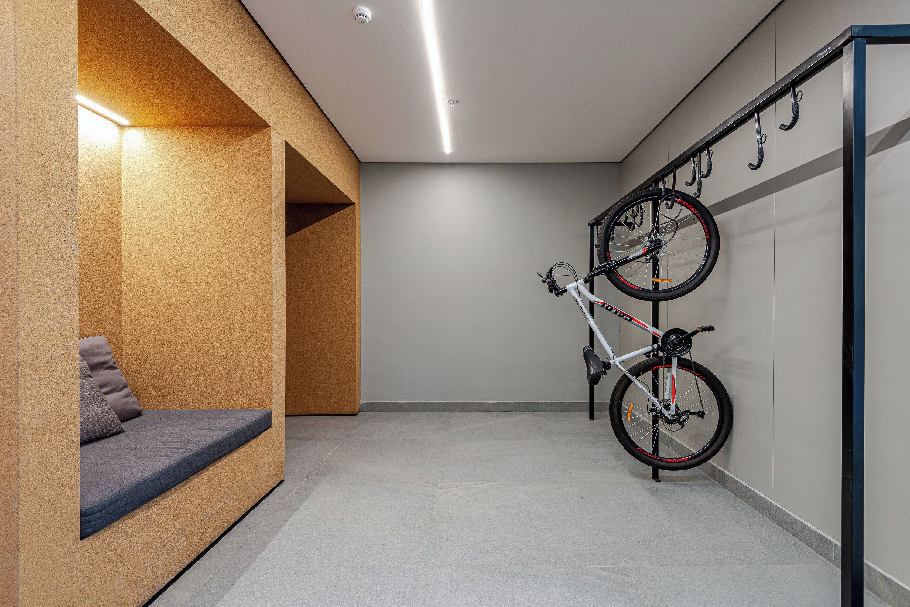 Un couloir avec un porte-vélos, un banc et un vélo fixé au mur.