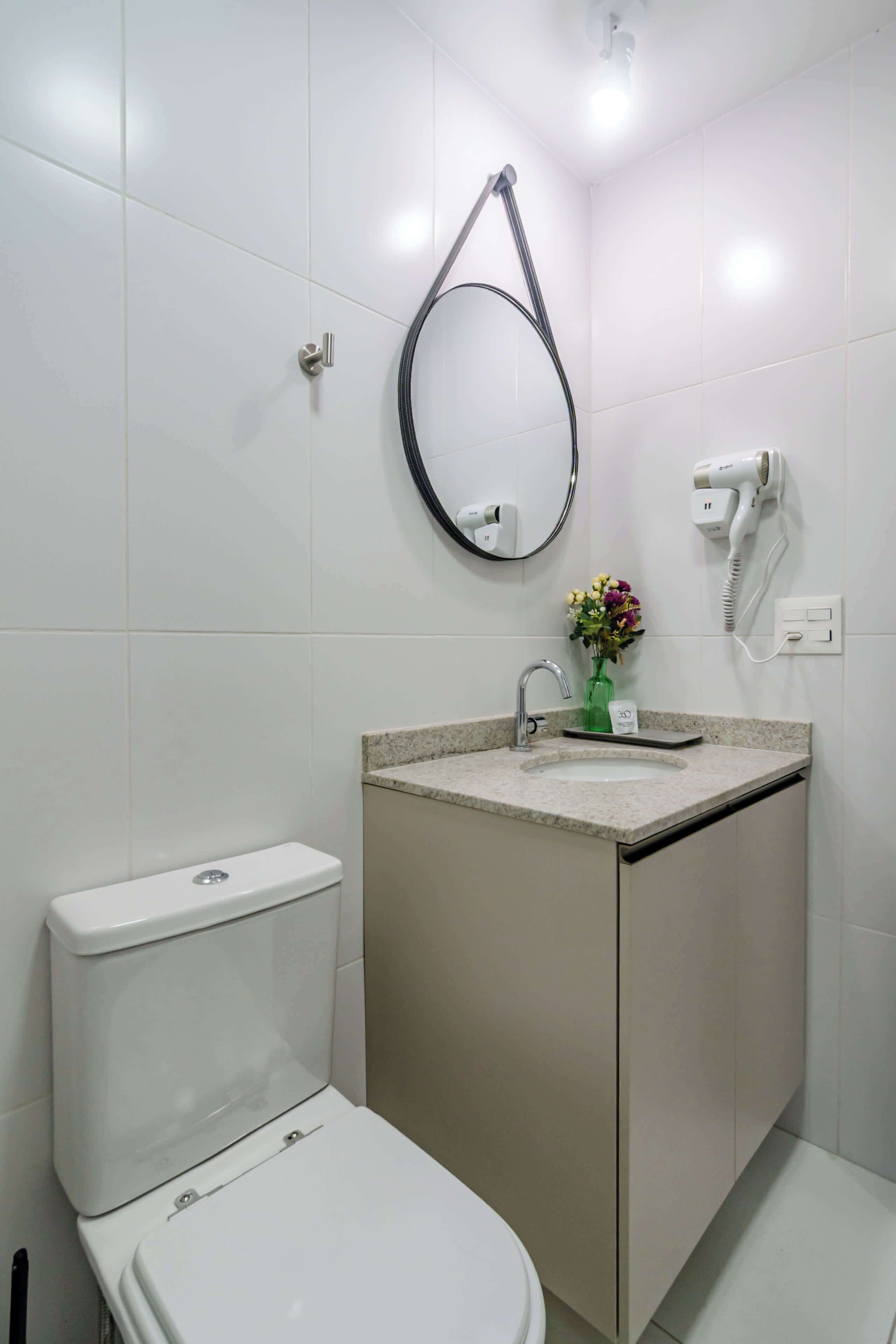 Un baño con inodoro, lavabo, espejo y secador de pelo.