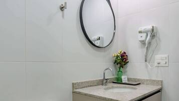 Un baño con inodoro, lavabo, espejo y secador de pelo.