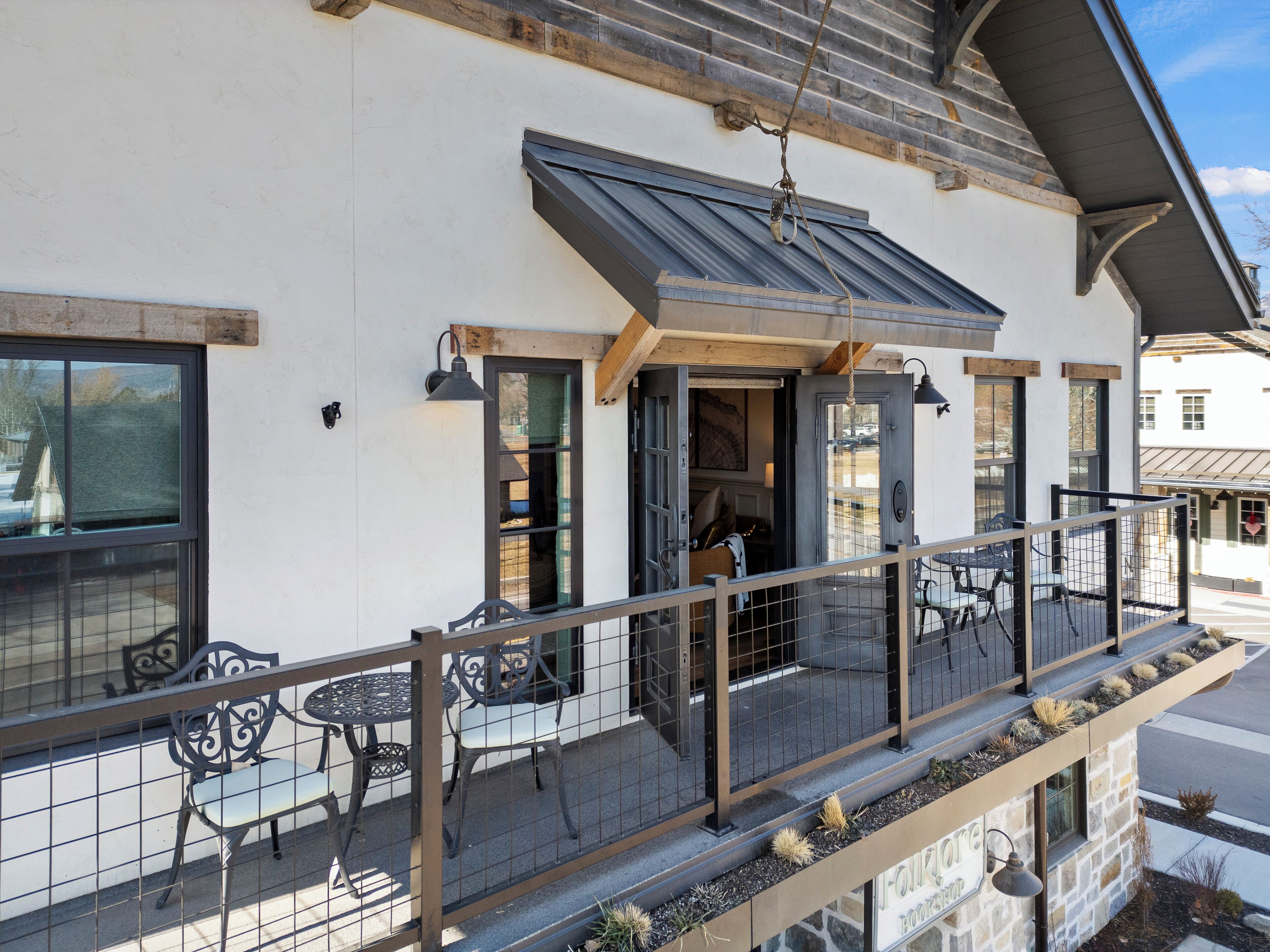 A building with a balcony, outdoor seating, and a stone facade.