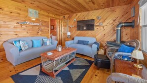 A cozy cabin interior with a wooden interior, a sofa, a coffee table, and a fireplace.