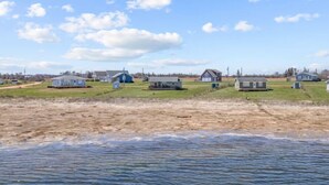 A coastal area with several small houses and trailers, a sandy beach, and a body of water.