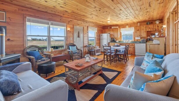 A cozy cabin interior with wooden walls, a dining area, and a kitchen.