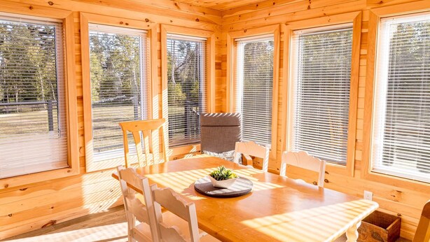 Ein Holzblockbau-Innenraum mit Esstisch, Stühlen und einer kleinen Pflanze auf dem Tisch.