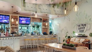 Un café chaleureux avec un coin bar, des places assises et une fresque murale.