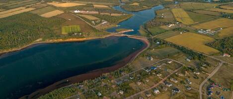Vue aérienne d’une communauté riveraine, avec des zones résidentielles, des routes et un pont reliant l’endroit à une étendue d’eau plus vaste.