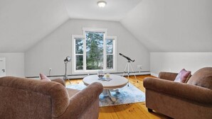 A cozy living room with two brown sofas, a round coffee table, and a large window with a tripod. - 3-Bedroom Chalet with Kayak in private community - minutes to Cavendish Beach (North Rustico)