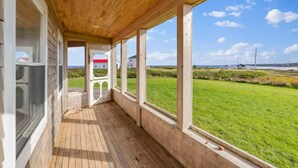 Une véranda en bois, dotée de grandes fenêtres donnant sur un paysage verdoyant.