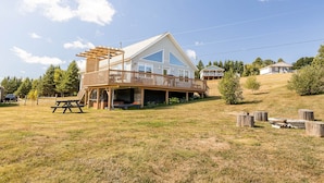 A two-story house with a wooden deck and a covered patio area. - Riverside Summer Retreat on PEI with Hot Tub, Deck, Kayaks & Pet-Friendly Stay (Prince Edward Island)