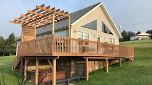 A two-story house with a wooden deck and a covered outdoor seating area. - Riverside Summer Retreat on PEI with Hot Tub, Deck, Kayaks & Pet-Friendly Stay (Prince Edward Island)