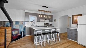 Una cocina moderna con una isla central, taburetes de bar, horno empotrado y estufa.
