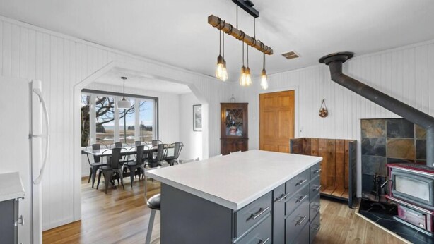 Una cocina moderna con una isla central, armarios de madera e iluminación colgante.
