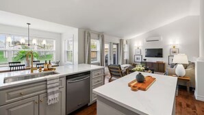 A modern kitchen with a dishwasher, a sink, and a dining area with a table and chairs. - Stylish Stratford Home Near Charlottetown—Spacious, Family-Friendly Retreat (Stratford)