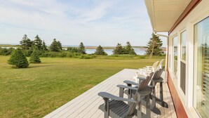 A deck with chairs overlooking a lake and forest.