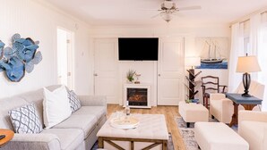 Un salon avec une cheminée, un téléviseur et un ventilateur de plafond.