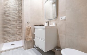 Une salle de bain moderne équipée d’une douche, de toilettes et d’un meuble-lavabo.