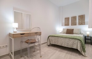 Une chambre à coucher comprenant un lit, un bureau avec une chaise, un miroir et des œuvres d’art mural.
