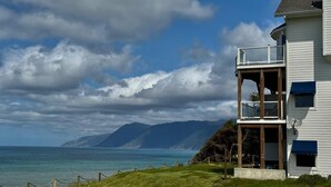 A two-story house with a balcony overlooking a coastal view. - Seagull by OceanviewHotTubs Oceanfront Tesla charging Oceanfront Shelter Cove (Whitethorn)