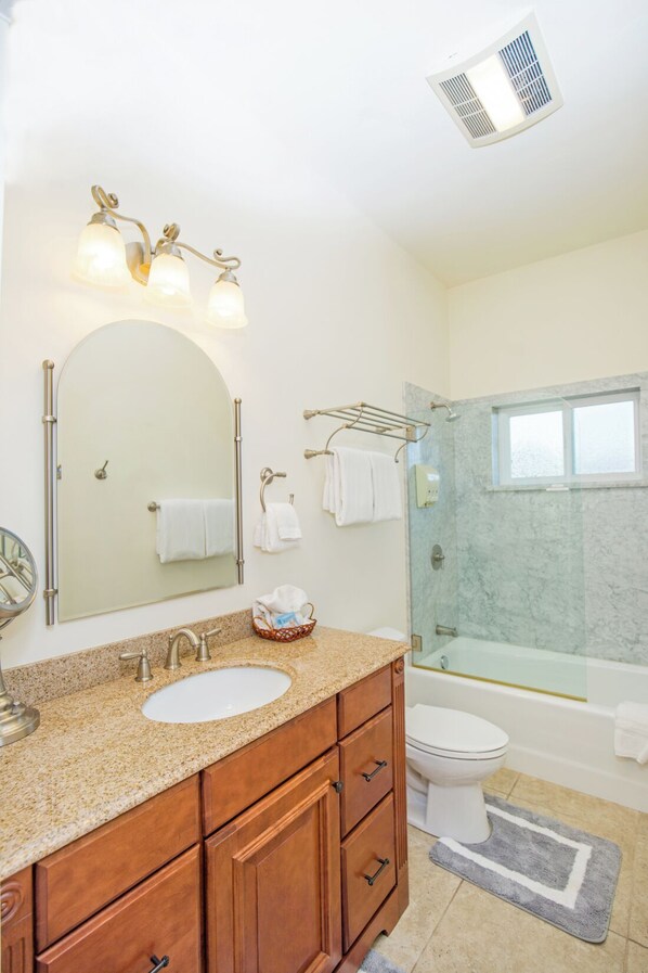 A bathroom with a vanity, sink, mirror, towel rack, and a glass-enclosed shower area.