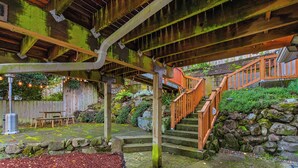 A covered outdoor area with a wooden staircase, stone walls, and a picnic table. - Green Lake Zen Low Level Garden Suite (Seattle)