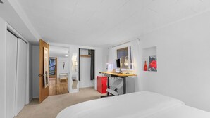 A modern hotel room with a bed, a desk, a red cabinet, and a mirror. - Green Lake Zen Low Level Garden Suite (Seattle)