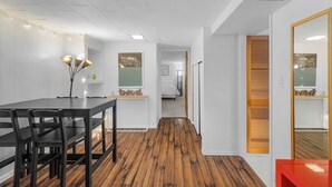 A modern hotel room with a wooden floor, a dining area with a table and chairs, a mirror, and a small kitchenette. - Green Lake Zen Low Level Garden Suite (Seattle)