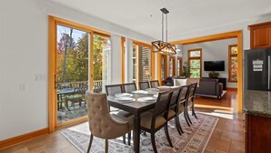 A spacious dining area with a large table set for six, surrounded by wooden chairs.