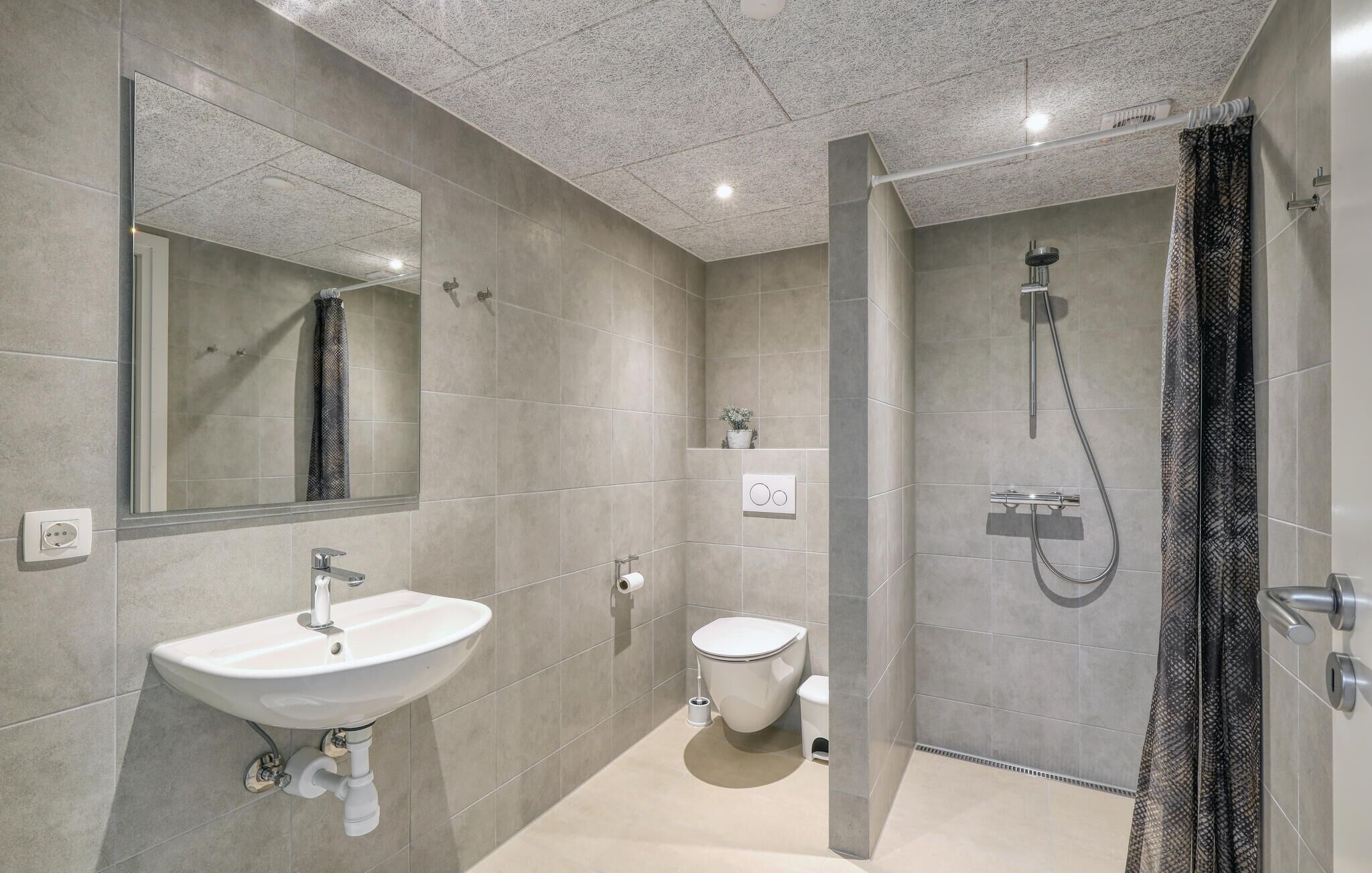 A modern bathroom with a sink, toilet, and shower.