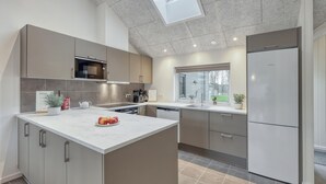 Une cuisine moderne dotée d’un îlot central, d’appareils électroménagers intégrés et d’une lucarne.