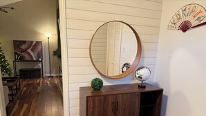 A wooden console with a round mirror and a globe on top, against a white paneled wall. - Beach house - 2 min from Conimicut Beach (Warwick)