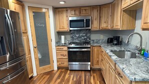 A modern kitchen with wooden cabinets, stainless steel appliances, and a granite countertop. - Beach house - 2 min from Conimicut Beach (Warwick)