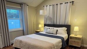 A neatly made bed with a headboard, two bedside lamps, and a window with curtains. - Beach house - 2 min from Conimicut Beach (Warwick)