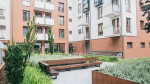 Un moderno edificio de apartamentos con varios balcones, un patio central con un banco de madera y una combinación de paredes de ladrillo y blanco.