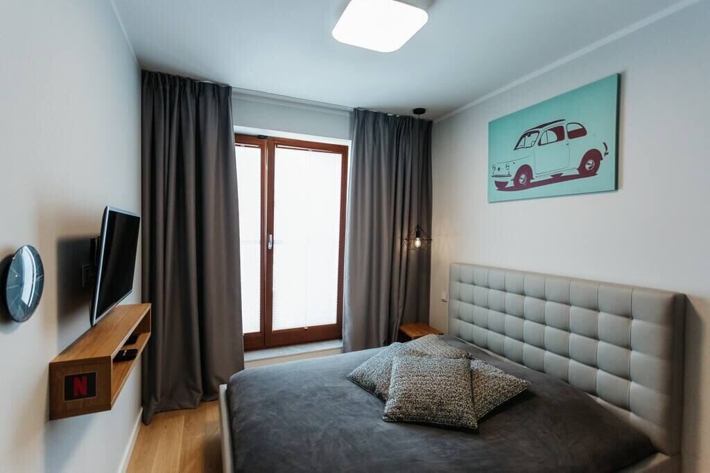 A modern bedroom with a bed, a TV, and a painting of a car.