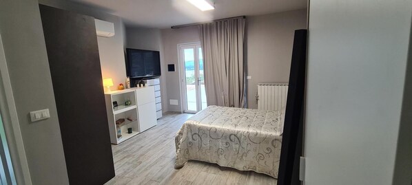 A bedroom with a bed, a TV, a desk, and a window with curtains. - VILLA FIORITA STUDIO APARTMENT LAKE VIEW  (Avigliana)