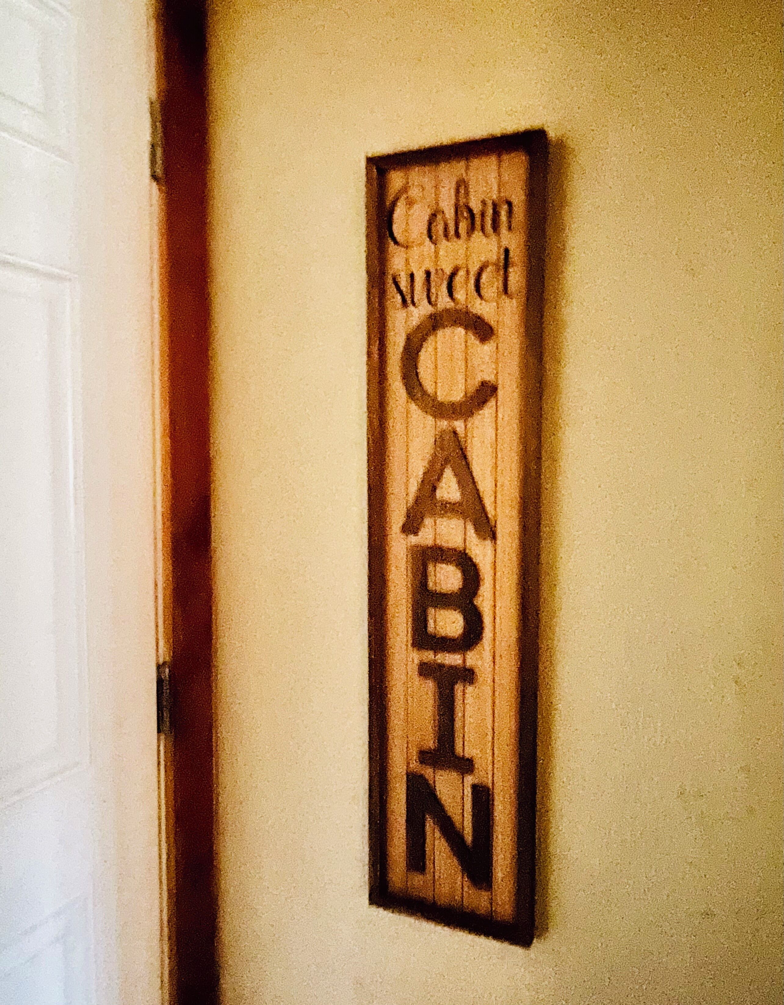 A wooden sign with the words "Cabin Sweet Cabin" mounted on a wall.