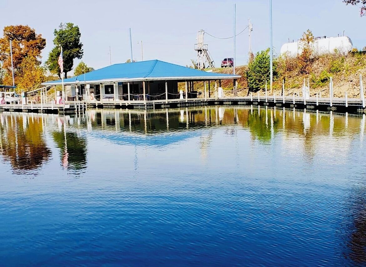 A calm water body with a docked boat and a building with a blue roof.