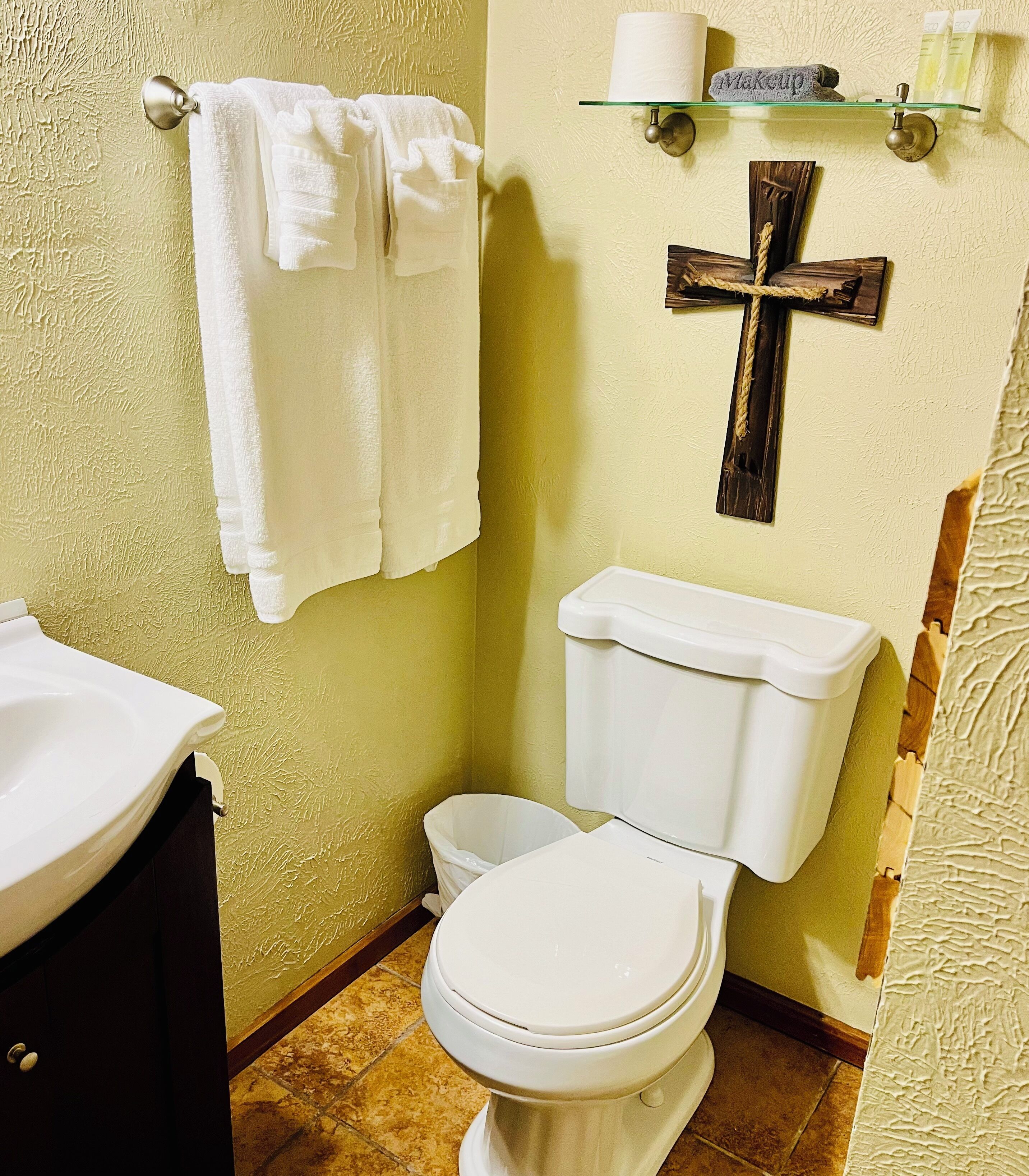 A bathroom with a toilet, sink, and a towel rack with multiple towels.