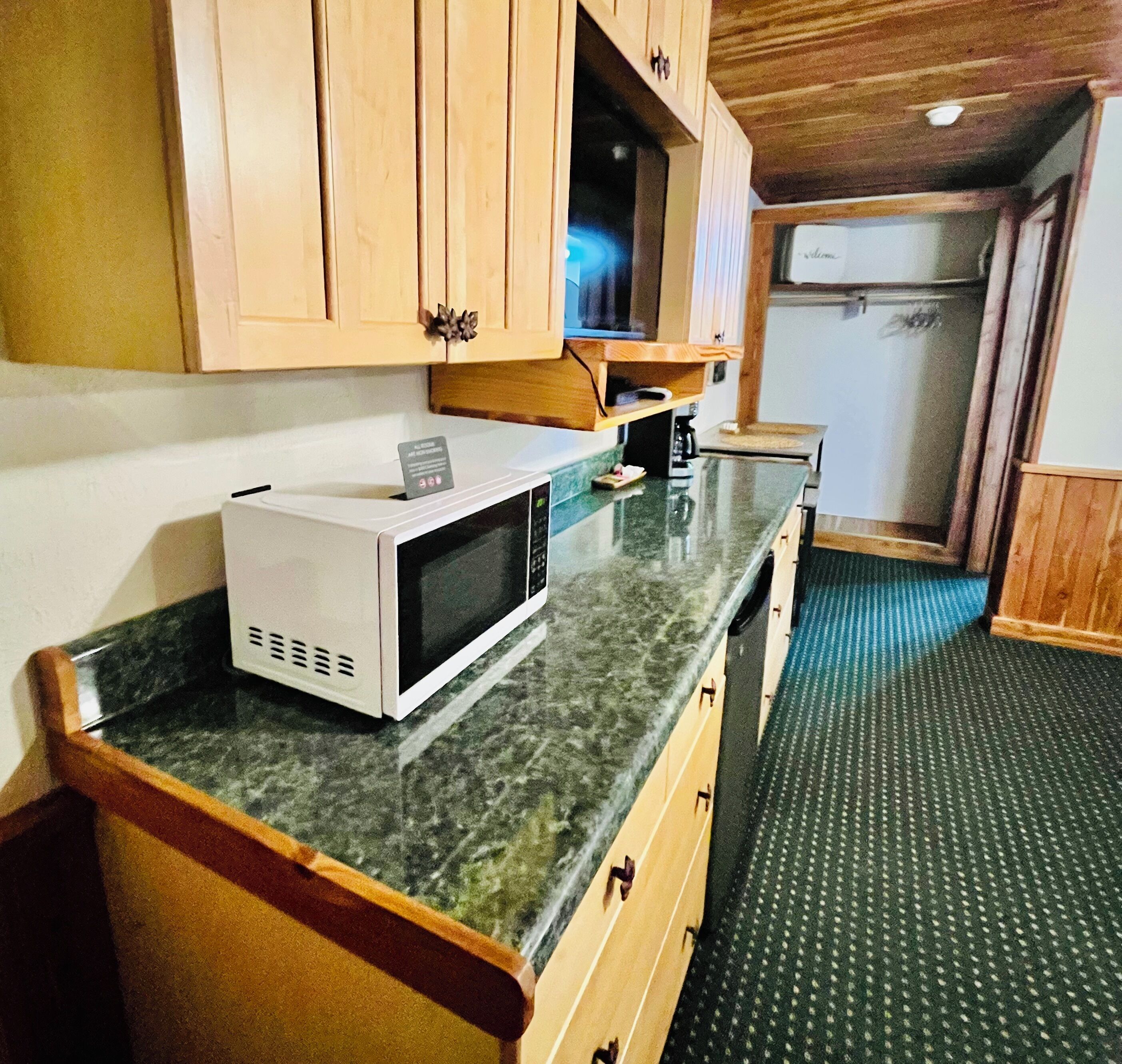 A kitchen with wooden cabinets, a microwave, a coffee maker, and a small television.