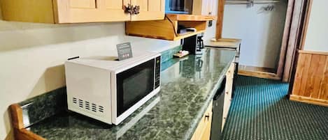 A kitchen with wooden cabinets, a microwave, a coffee maker, and a small television.