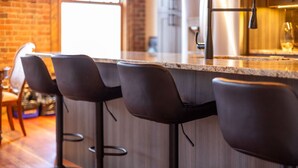 A bar area with a wooden counter and four black bar stools. - Amazing Downtown Location. Sleeps 7. Dog Friendly (Fernie)
