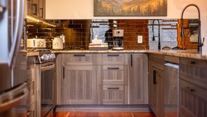 A modern kitchen with wooden cabinets, a coffee maker, and a toaster. - Amazing Downtown Location. Sleeps 7. Dog Friendly (Fernie)