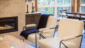Un salon chaleureux avec une cheminée, des sièges confortables et une vue dégagée grâce à de grandes fenêtres.