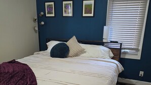 Une chambre à coucher avec un lit, une table de chevet, une lampe et une fenêtre avec des stores.