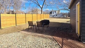 Un espace extérieur aménagé en terrasse, avec un sol en gravier, deux chaises et un barbecue.
