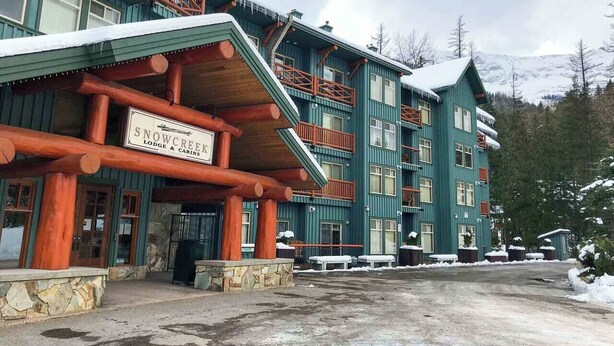 Eine Lodge mit Holzfassade, mehreren Balkonen und einem Schild, das anzeigt, dass es sich um das Snow Creek Lodge & Cabins handelt.