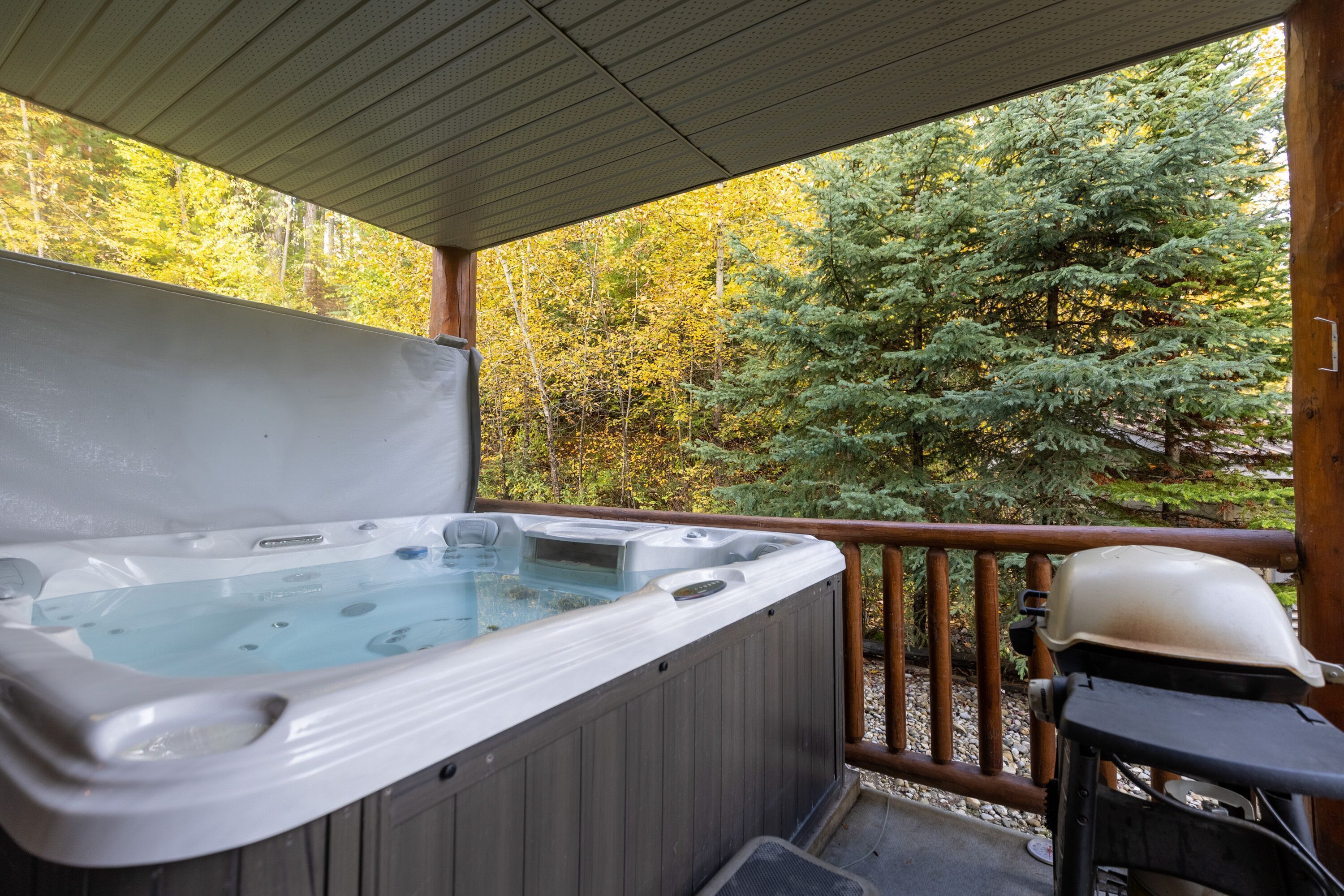 Een hottub op een houten terras met uitzicht op een bos.